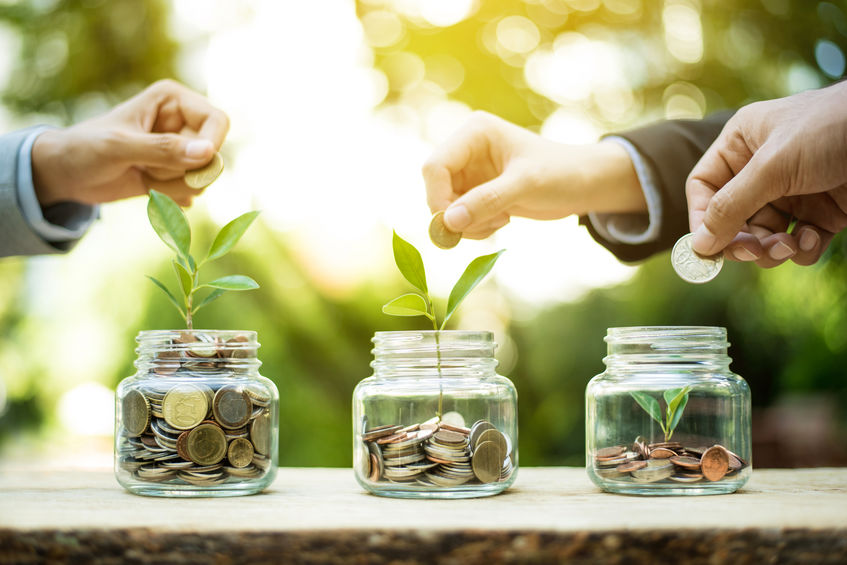 Des mains déposent de l'argent dans des boîtes illustrant l'optimisation des revenus et la croissance en portage salarial